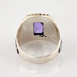 Nahaufnahme eines antiken Metallrings mit Innenprägung '906M' und violettem quadratischem Schmuckstück