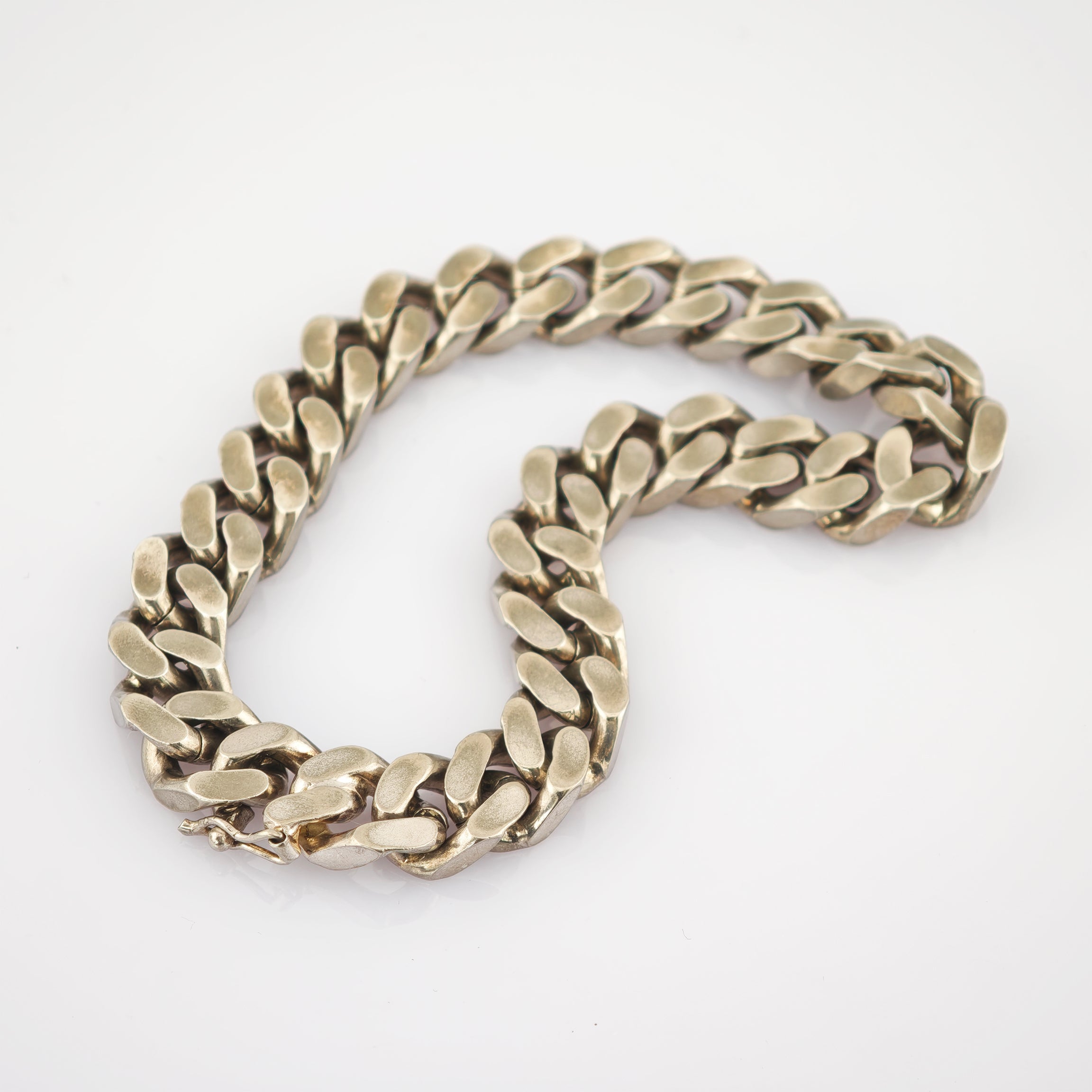Dickes goldfarbenes Armband mit breiten, strukturierten Gliedern und sichtbarem Verschluss auf weißem Hintergrund.