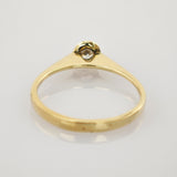 Eleganter Goldring mit kleinem Diamanten im minimalistischen Design auf hellgrauem Hintergrund.