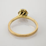 Eleganter Goldring mit schlanker Bandschiene und erhöhter Fassung für einen Edelstein auf weißem reflektierendem Untergrund.
