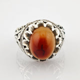 Eleganter Silberring mit ovalem rot-orangefarbenem Stein und filigranem Blatt- und Rankenmuster.