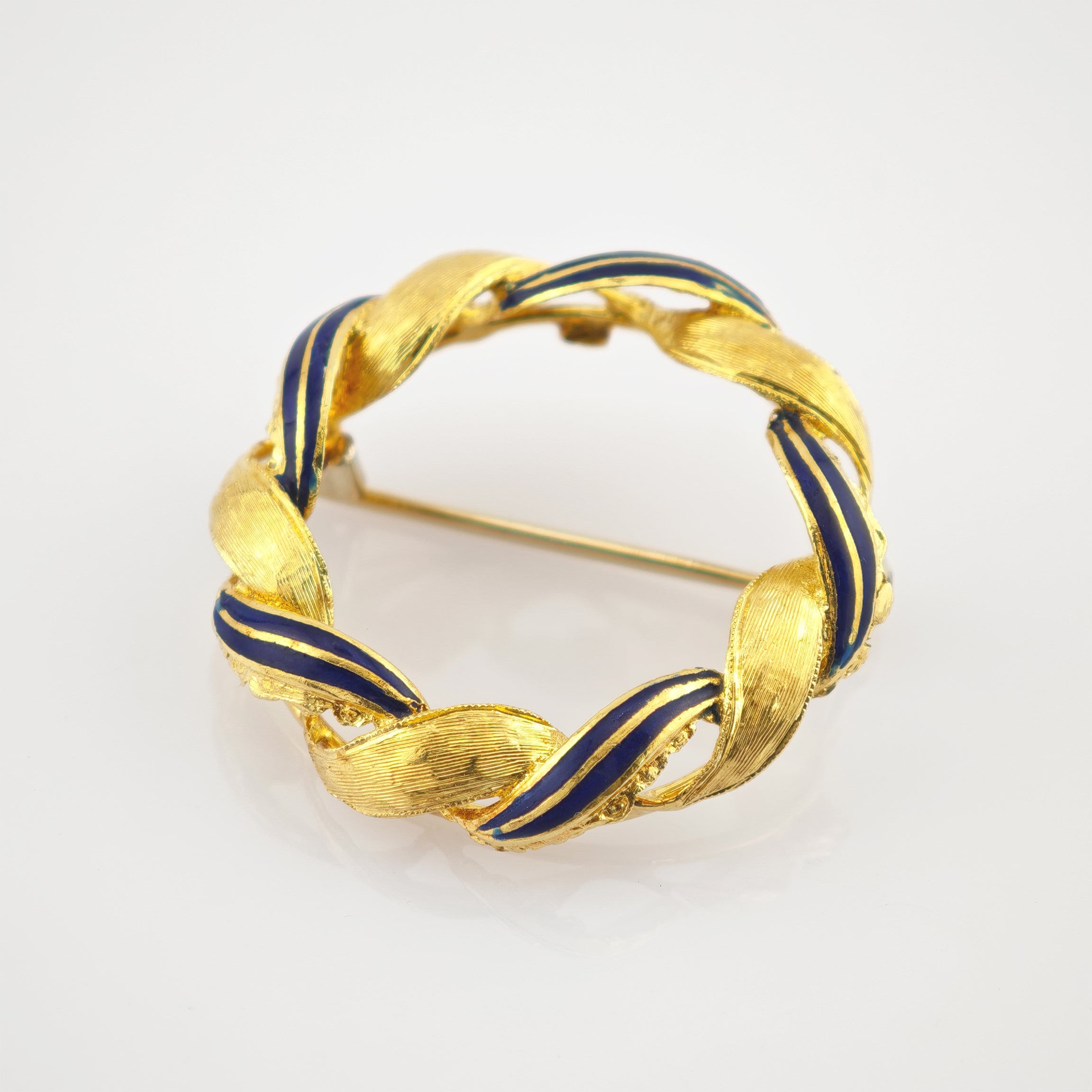 Fein gearbeitete runde Brosche mit gedrehtem Band aus strukturiertem Gold und dunkelblauen Emaille-Segmenten.