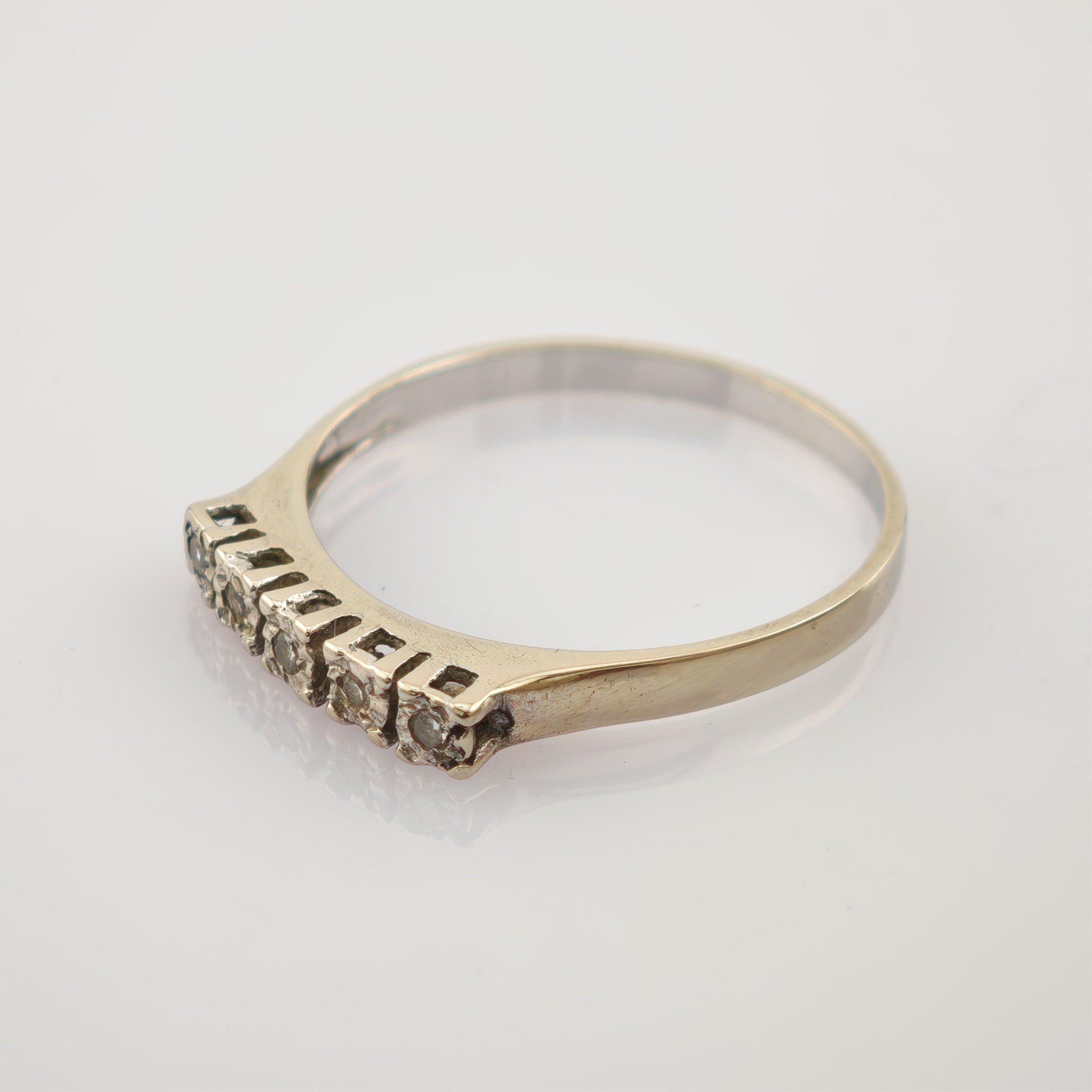 Feiner Goldring mit schmalem Band und fünf kleinen runden Steinen, 14K markiert.