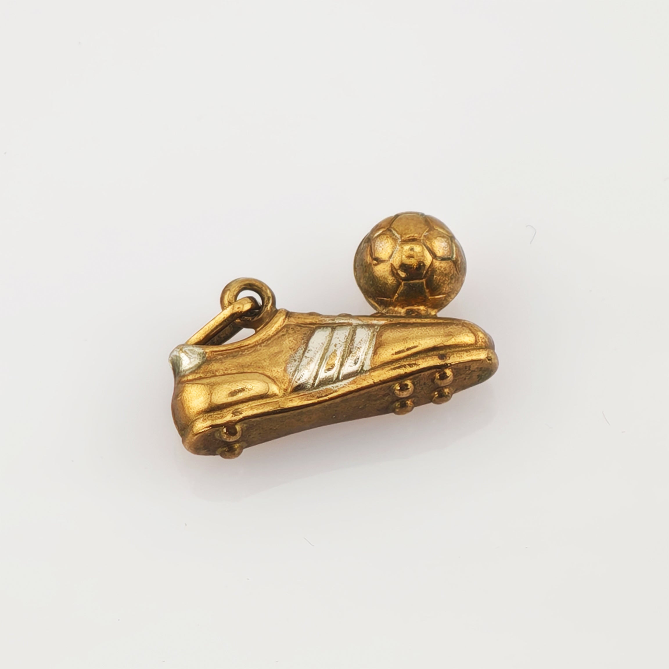 Goldener Anhänger in Fußballschuhform mit silbernen Streifen und kleinem Fußball mit hexagonalen Mustern.