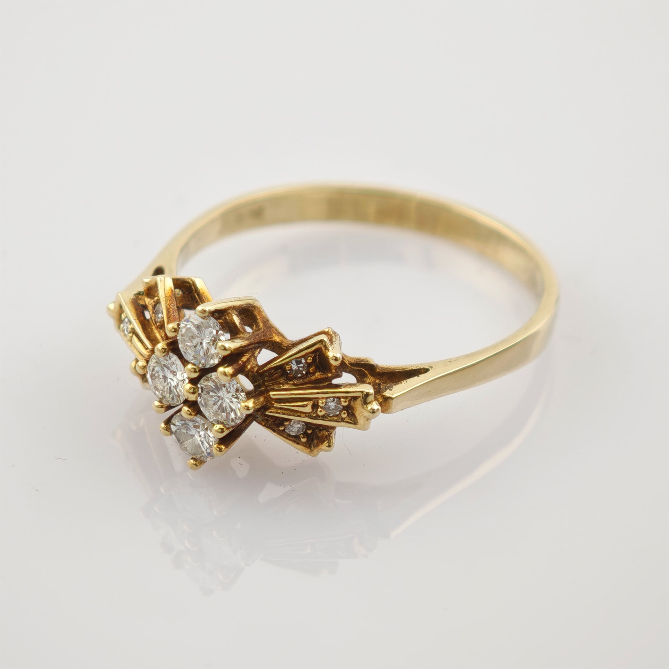 Goldener Ring mit feinem Design und sieben kleinen, runden weißen Steinen in Kreuzanordnung auf schmalem Band.
