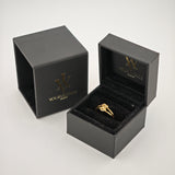 Goldener Knotenring in offenem schwarzen Samt-Ringkästchen mit goldfarbenem Logo.