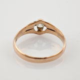 Nahaufnahme eines goldenen Rings mit klarem Edelstein in Krappenfassung auf weißem Hintergrund.