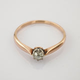 Goldener Ring mit klarem Einzelstein in Drahtfassung auf schlichtem Hintergrund
