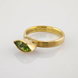Goldener Ring mit matt gebürstetem Band und grünem Marquise-Edelstein im Facettenschliff.