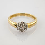 Goldener Ring mit rundem Cluster aus kleinen Diamanten, silberne Fassung, glänzende weiße Oberfläche.
