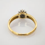 Goldener Ring mit vier weißen Steinen auf polierter Oberfläche.