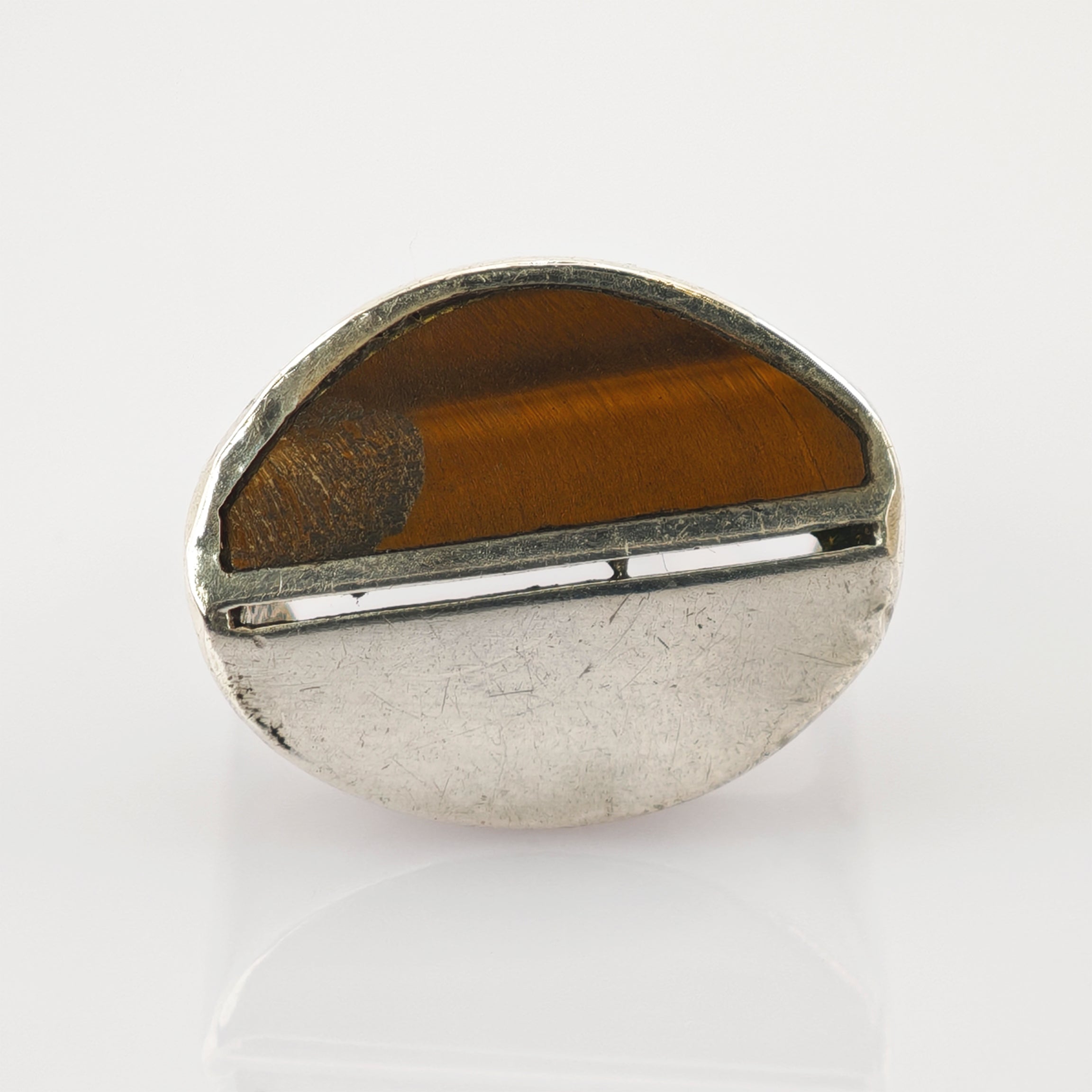 Ovaler Ring mit poliertem braunem Tigerauge und strukturiertem silbernen Metallband auf weißem Hintergrund.