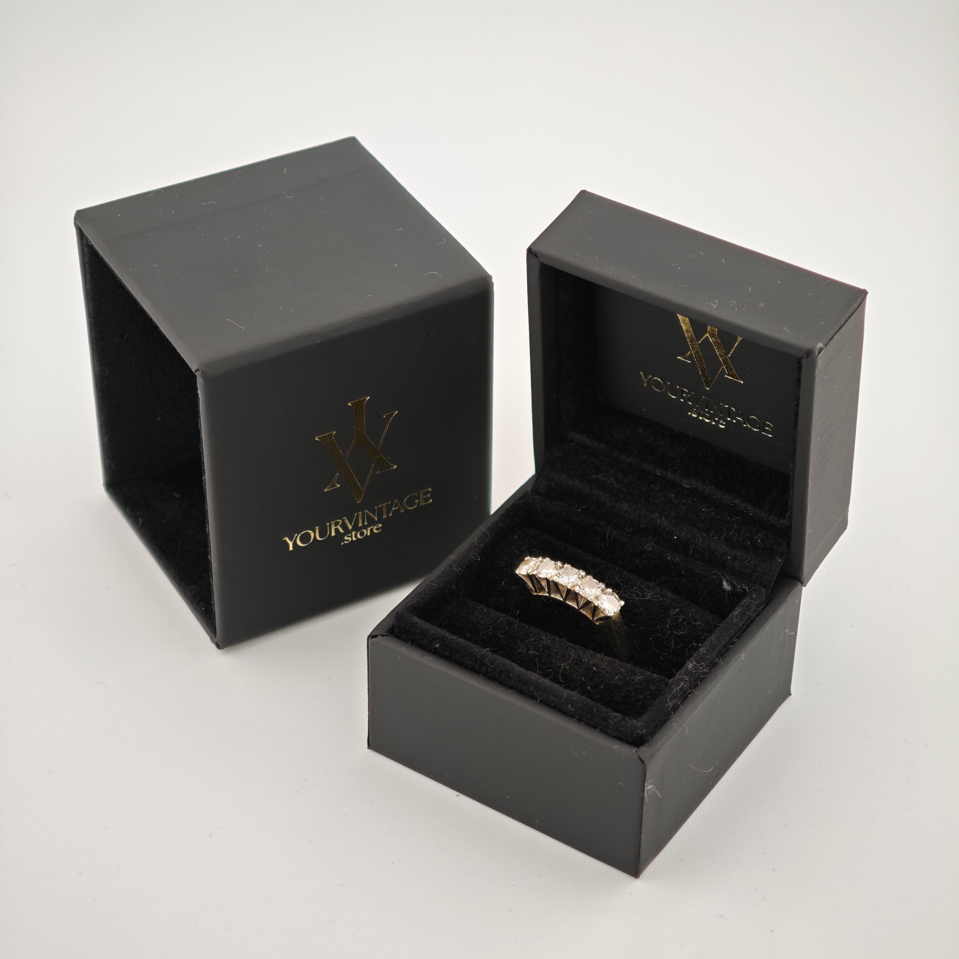 Geöffnete schwarze Schmuckbox mit goldfarbenem Ring und Diamanten auf schwarzem Samt, mit goldenem yourvintoge.shop Logo.