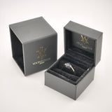 Schwarze Ringbox mit Samtfutter zeigt goldenen Ring mit dunklem Stein und zwei kleinen Seitsteinen, IhrVintage Store Logo.