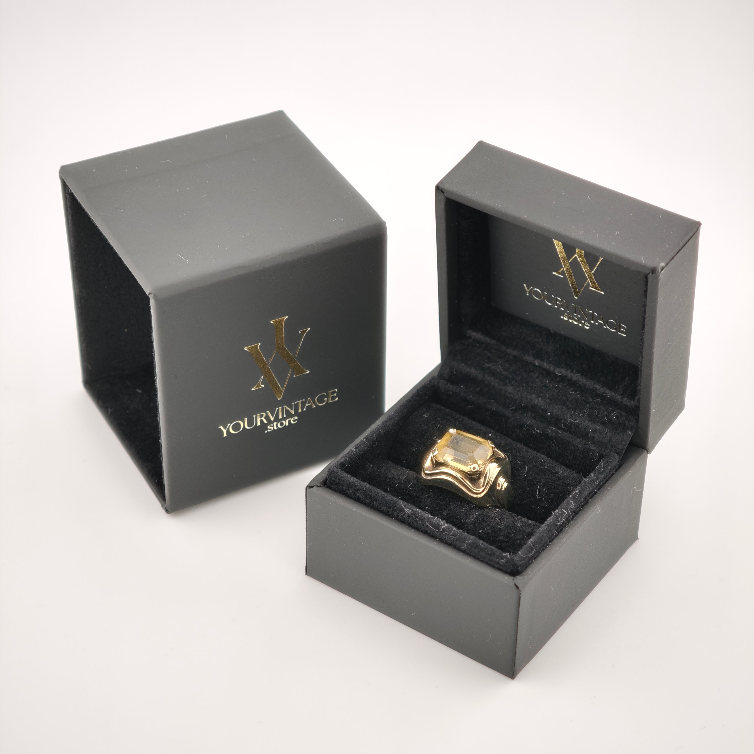 Schwarze Schmuckschachtel mit goldfarbenem Ring und rechteckigem Edelstein, goldenes Logo yourvintoge.shop