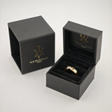 Schwarze Schmuckschachtel mit goldenem Logo und Goldring auf schwarzem Samtkissen