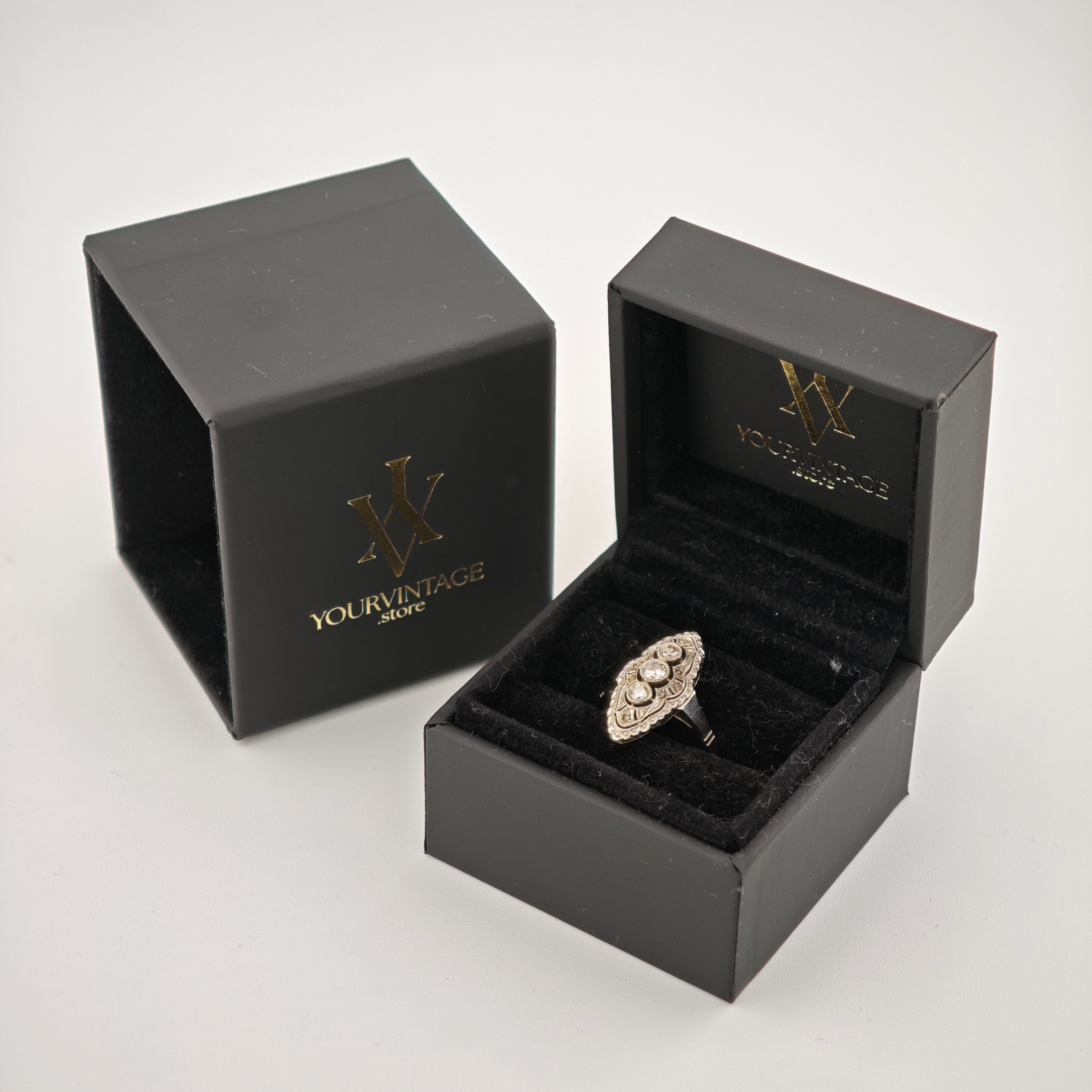 Schwarze Schmuckschatulle mit goldenem yourvintoge.shop Logo, offene Box zeigt silbernen Ring mit drei Steinen