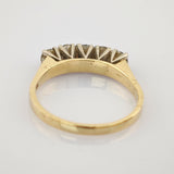 Seitliche Ansicht eines Goldrings mit fünf Diamanten, gehalten von silbernen Krappen, auf weißem Untergrund.
