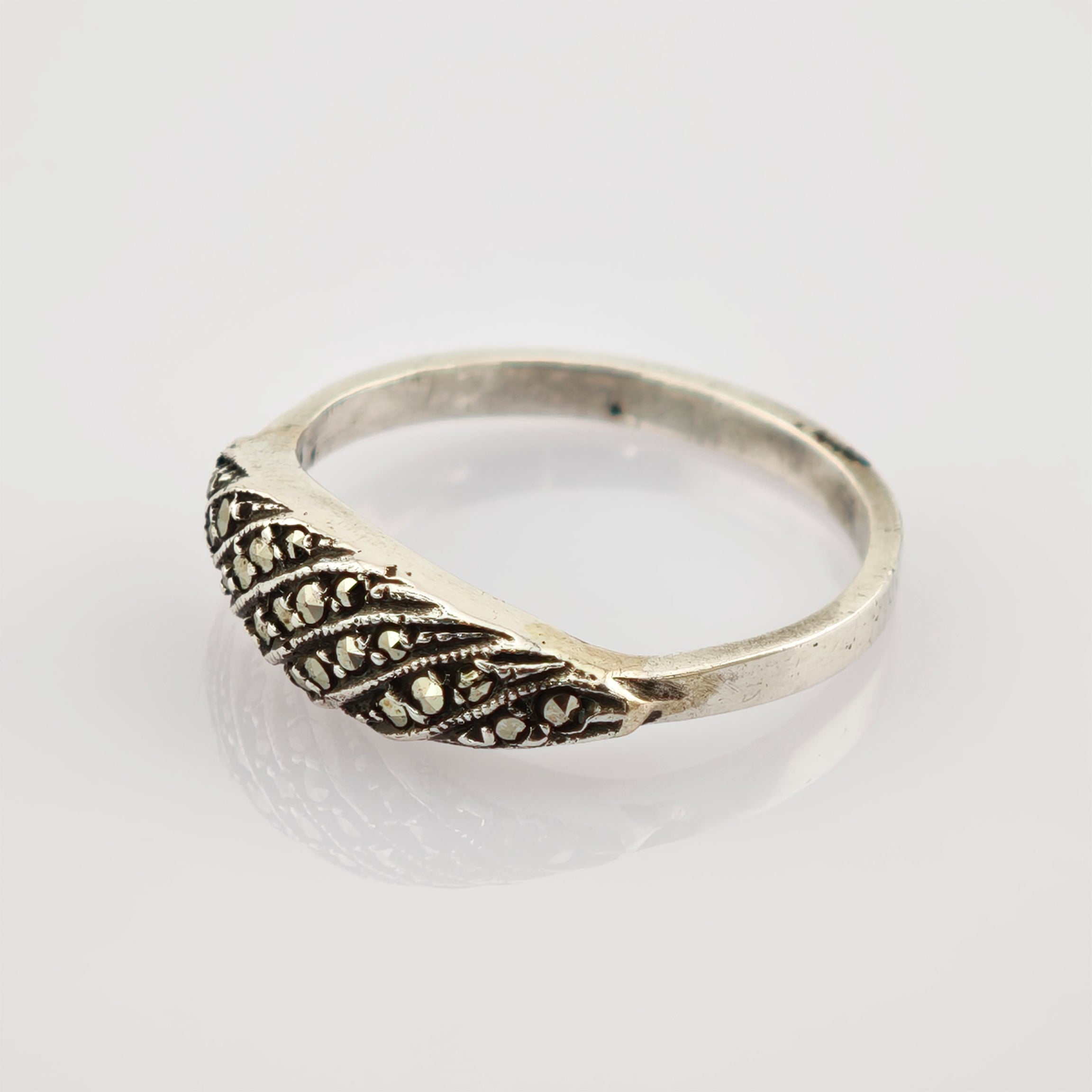 Silberner Ring mit diagonalen Verzierungen auf weißer Oberfläche