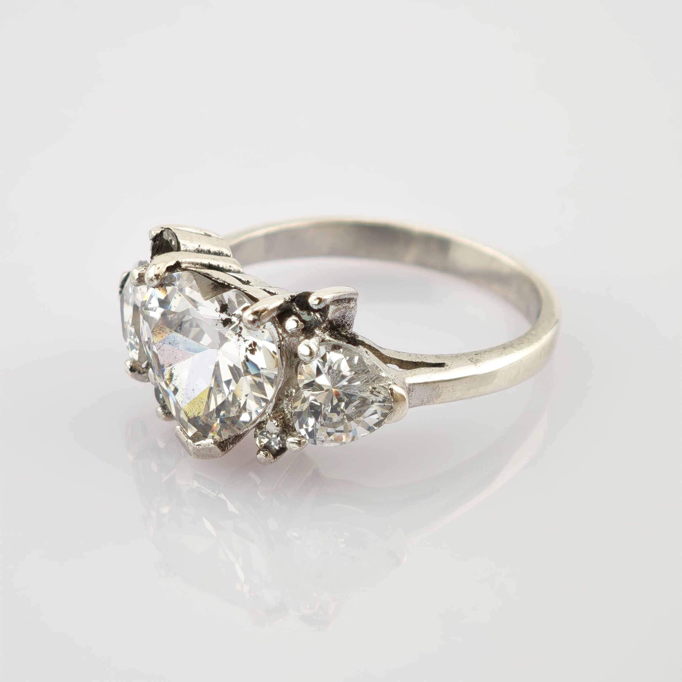 Eleganter silberner Ring mit herzförmigem und dreieckigen Edelsteinen auf schlichtem Band