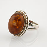Eleganter silberner Ring mit großem ovalem Bernstein und gedrehtem Seildetail
