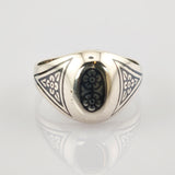 Silberner Ring mit ovalem schwarzen Mittelstück und weißen Blumenmustern in Dreiecksform