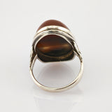 Silberner Ring mit ovalem braunem Stein und poliertem Metallband, seitliche Ansicht