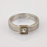 Silberner Ring mit quadratischer Fassung und klar geschliffenem Edelstein.