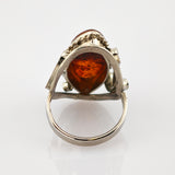 Silberner Ring mit tropfenförmigem Bernstein und kunstvoller Silberfassung, Vorderansicht