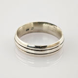 Silberner Vintage-Ring mit zwei parallel verlaufenden Rillen und leichter Patina auf weißem reflektierendem Untergrund.