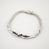 Silbernes Armband mit Diamantmuster und kleinen dunklen Edelsteinen in zwei mittleren Abschnitten.