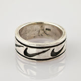 Silberner Vintage-Ring mit dunkel gefülltem Muster und Gebrauchsspuren auf reflektierender Oberfläche