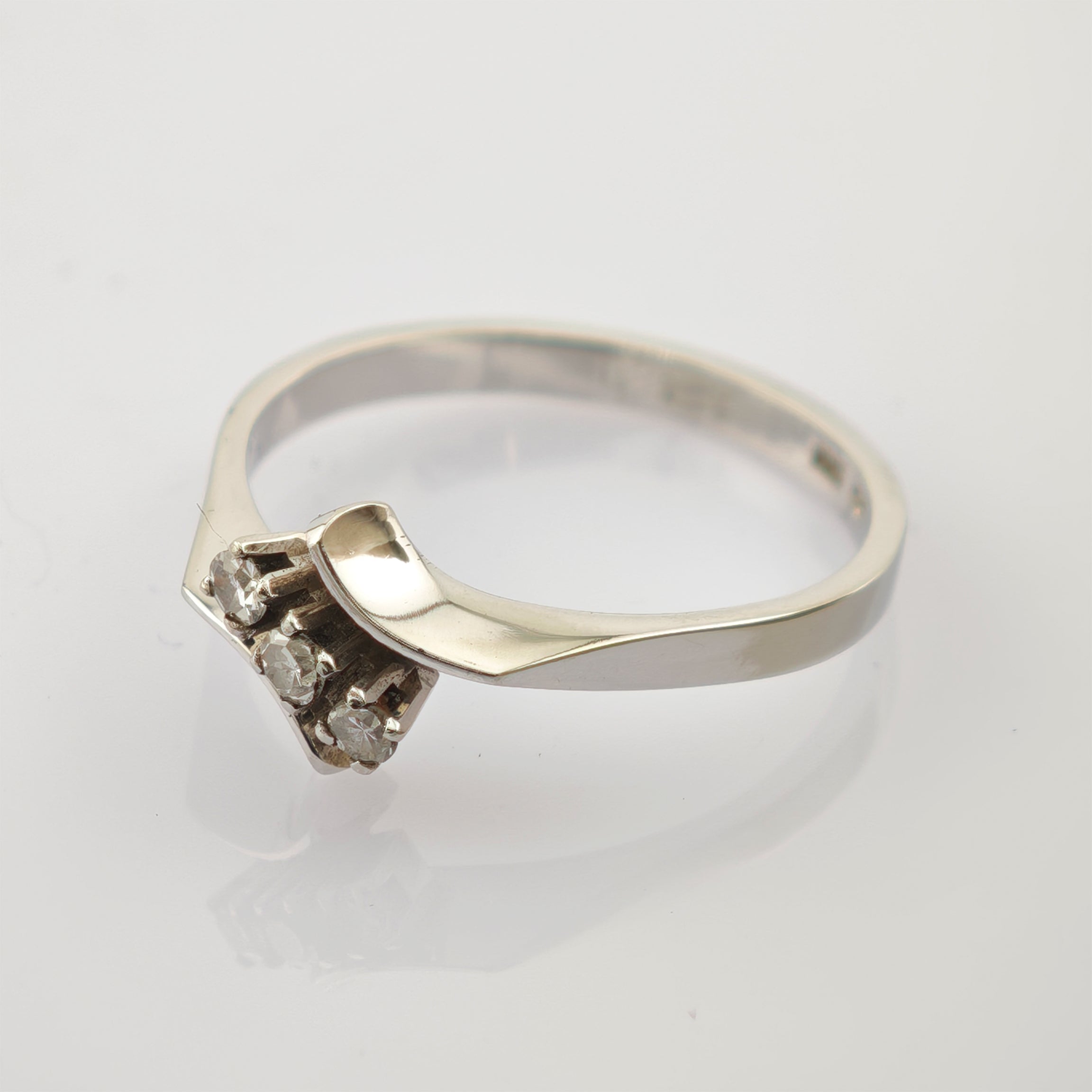 Eleganter Silberring mit drei kleinen runden Diamanten im Dreiecksmuster und gebogener Bandform.