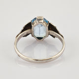 Rückseite von elegantem silbernernen Ring mit blauem trapezförmigem Edelstein und floralen Verzierungen.