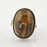 Silberring mit ovalem Cabochon-Stein und feinen goldenen Rutilnadeln im glatten Fassungsdesign.