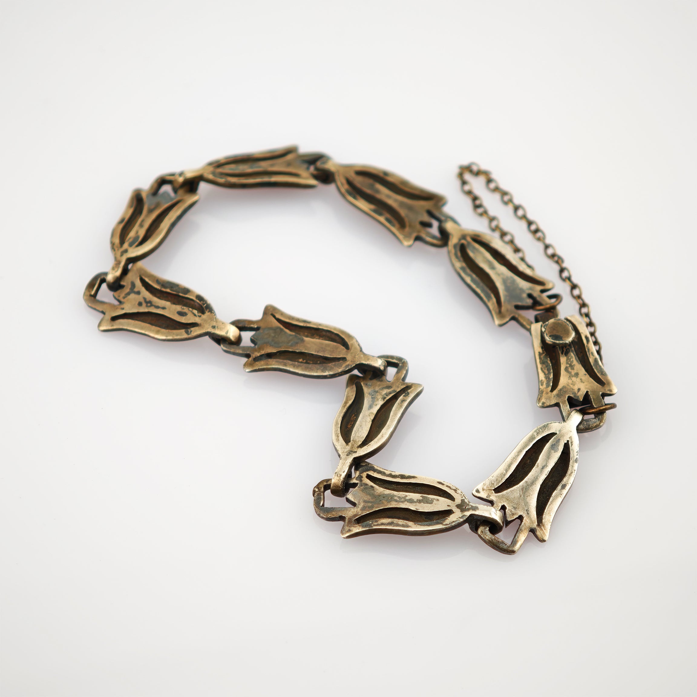 Vintagearmband aus miteinander verbundenen metallischen Blumelementen mit dunkler Patina und Sicherheitskette.